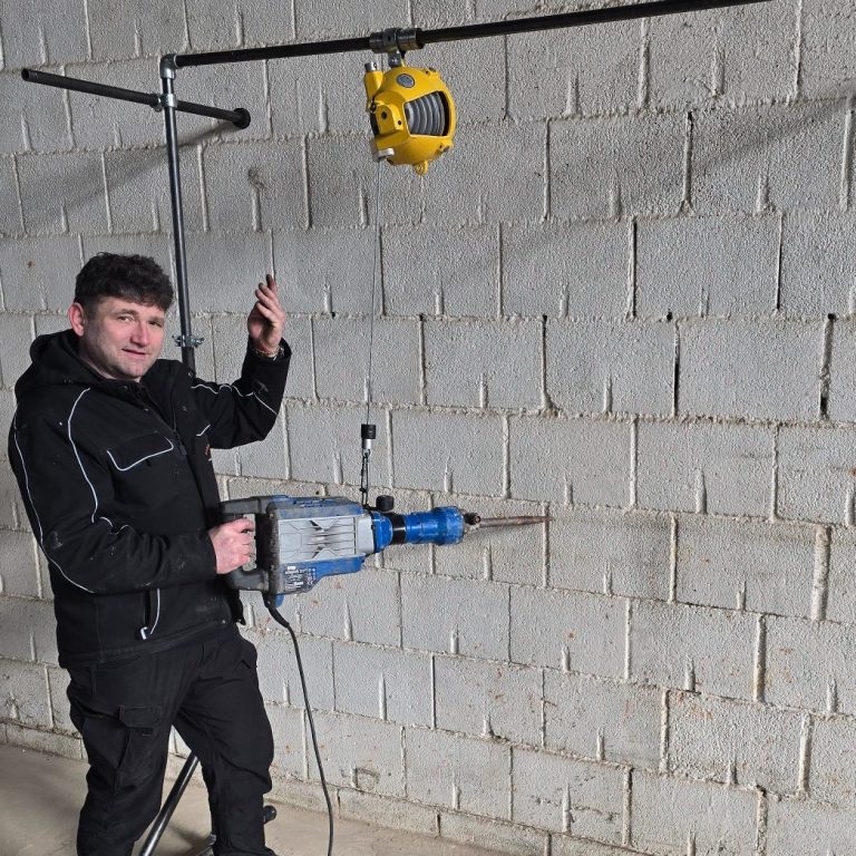 Arbeiter nutzt eine Mauersäge mit BalanToolce Balancer-System zur ergonomischen Unterstützung schwerer Handgeräte auf der Baustelle Arbeiter nutzt eine Mauersäge mit BalanToolce Balancer-System zur ergonomischen Unterstützung schwerer Handgeräte auf der Baustelle